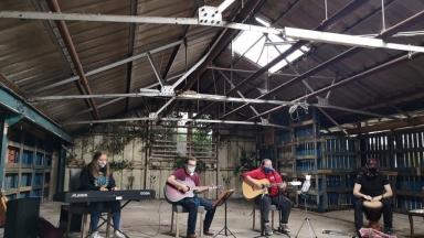 4 young people sitting 2 metres apart playing instruments